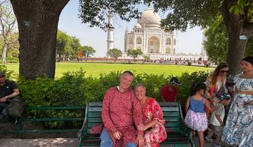 A couple sitting on a bench with the Taj Mahal in the background.