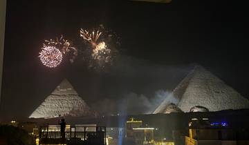Fireworks lighting up the night sky above pyramids.