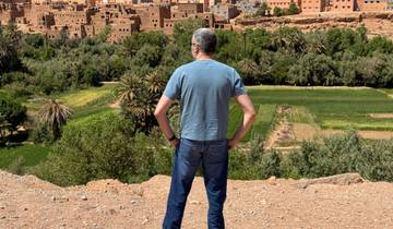 Man standing on a hill overlooking an oasis town.
