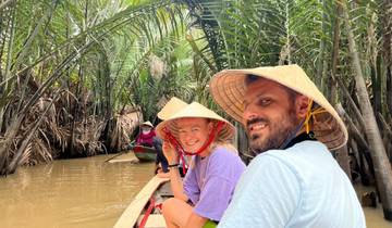 People in traditional hats on a river boat in a jungle.