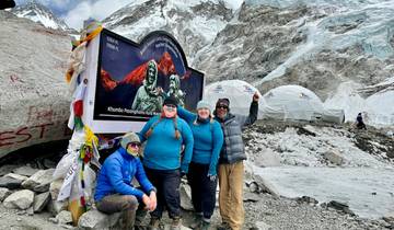 Group of hikers posing at Everest Base Camp with snowy mountains in the background.