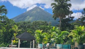 Arenal Volcano surrounded by lush greenery under a clear blue sky.