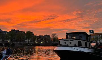 Boat docked at a canal during a stunning orange sunset.