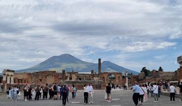 Ancient ruins with tourists and mountain backdrop.