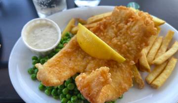 Fish and chips with peas and a lemon wedge.