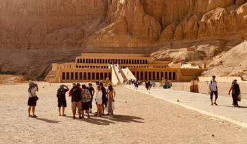Temple in desert landscape with tourists gathered in front.