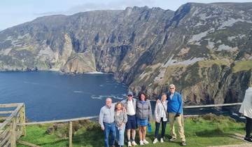 Group of people with a scenic coastal cliff background.
