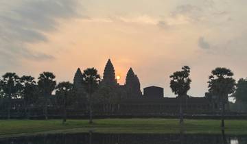 Angkor Wat at sunrise with palm trees in the foreground.