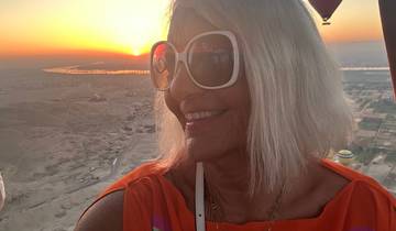 Woman enjoying a hot air balloon ride at sunset with expansive landscape views.
