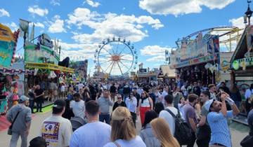 Crowded festival with fair rides under a clear sky.