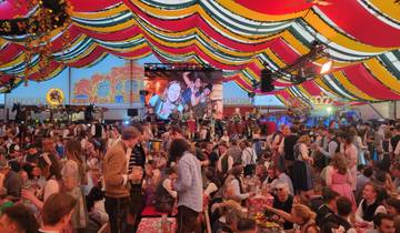 Inside a vibrant festival tent with many attendees.