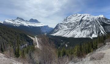 Scenic road flanked by snow-covered mountains.