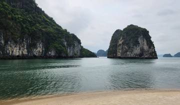 Scenic beach with water, trees, and rocky cliffs.