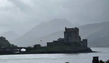 Castle on an island under a cloudy sky, with a bridge connecting it to the mainland.