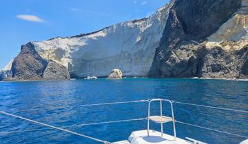 A boat on clear blue water with a backdrop of rocky cliffs.