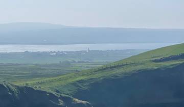 Scenic coastal view with distant town and sea.