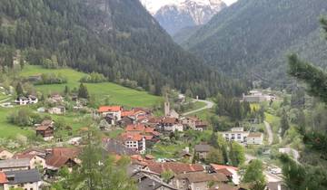Panoramic view of a lush valley with houses and winding roads.
