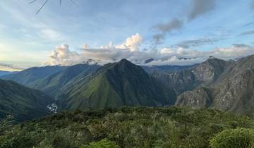 Mountainous landscape with green valleys under a cloudy sky.