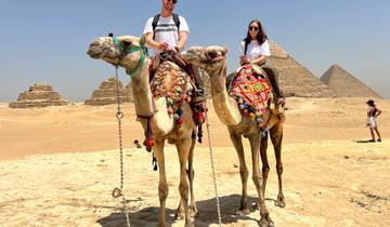 Tourists riding camels in front of the Pyramids of Giza.