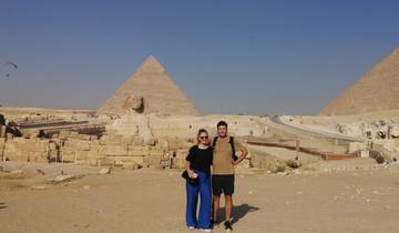 Tourists posing in front of pyramids and the Sphinx.