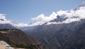 Snowy peaks and lush valleys under blue sky.