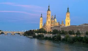 Illuminated basilica by the river in the evening.