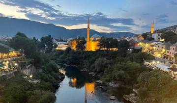 A scenic view of a river with illuminated buildings and a mosque.