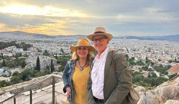 A couple posing with a cityscape view at sunset.