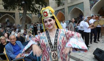 Woman in traditional dance costume amid a crowd.