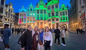 Family posing in front of illuminated historic buildings at night.