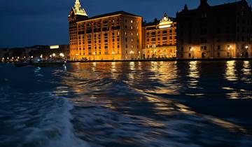 Illuminated building next to a waterway at night.