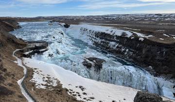 Frozen waterfall and icy river in a wide landscape.