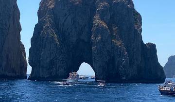 Boats near the Faraglioni rock formations in a blue sea.