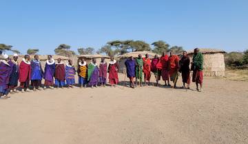 A line of traditionally dressed people in a rural setting with huts.