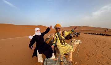 Two people on camels in the desert.