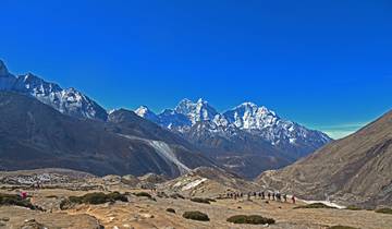 Panoramic view of snow-capped mountains with hikers in the distance.