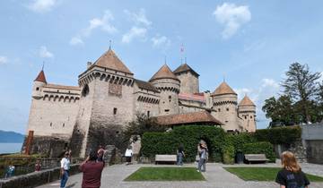 Tourists in front of a medieval castle with multiple towers.