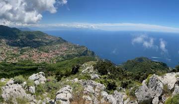 Panoramic view of mountains and a distant coastline with a cloudy sky.