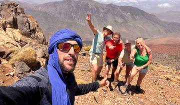 People posing on a rocky mountain landscape with a scenic view.