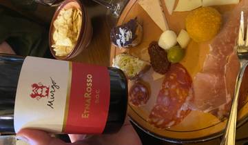 Wine and assorted meats and cheeses on a plate.