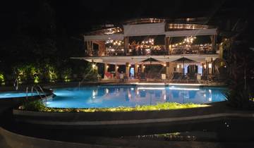 Outdoor pool and restaurant area with lights at night.