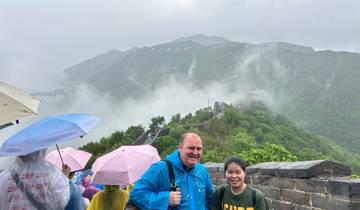 Tourists with umbrellas on a cloudy day at the Great Wall of China.