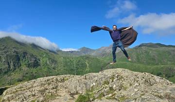 Man jumping on rocky terrain with mountains in the background.