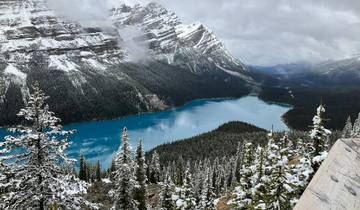 Panoramic view of a lake surrounded by snowy mountains.