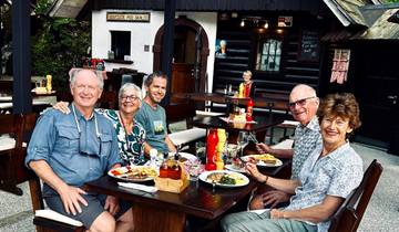 Group of people enjoying a meal outdoors at a restaurant.