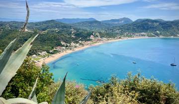 Panoramic view of a coastal town with blue waters and hills.