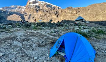 Tent set up at a base camp with mountain views in the background.