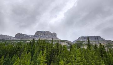 Mountain range with forested foothills under a cloudy sky.