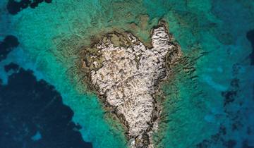 Aerial view of a small rocky island surrounded by blue water.