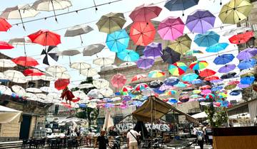 Street view with colorful umbrellas suspended over a cafe area.